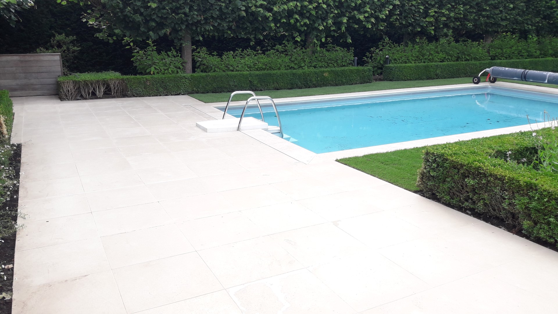 Luxeproject Brugge: Aanleg van terras in Libanese kalksteen met aansluitende zwembadboordstenen. Er zijn verdoken aquadrains ingewerkt in het terras