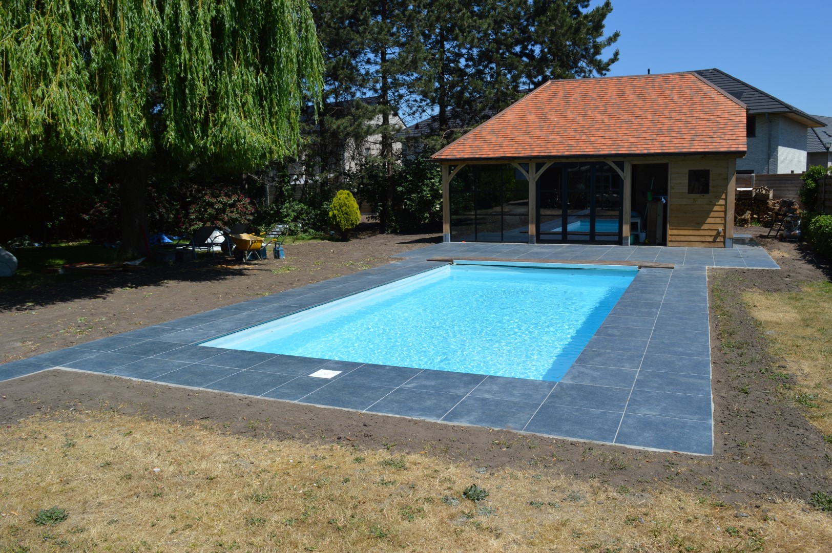 Luxeproject Evergem: bouwen van poolhouse met betonnen vloerplaat met een aangesloten, keramisch terras met zelfde zwembadboordstenen